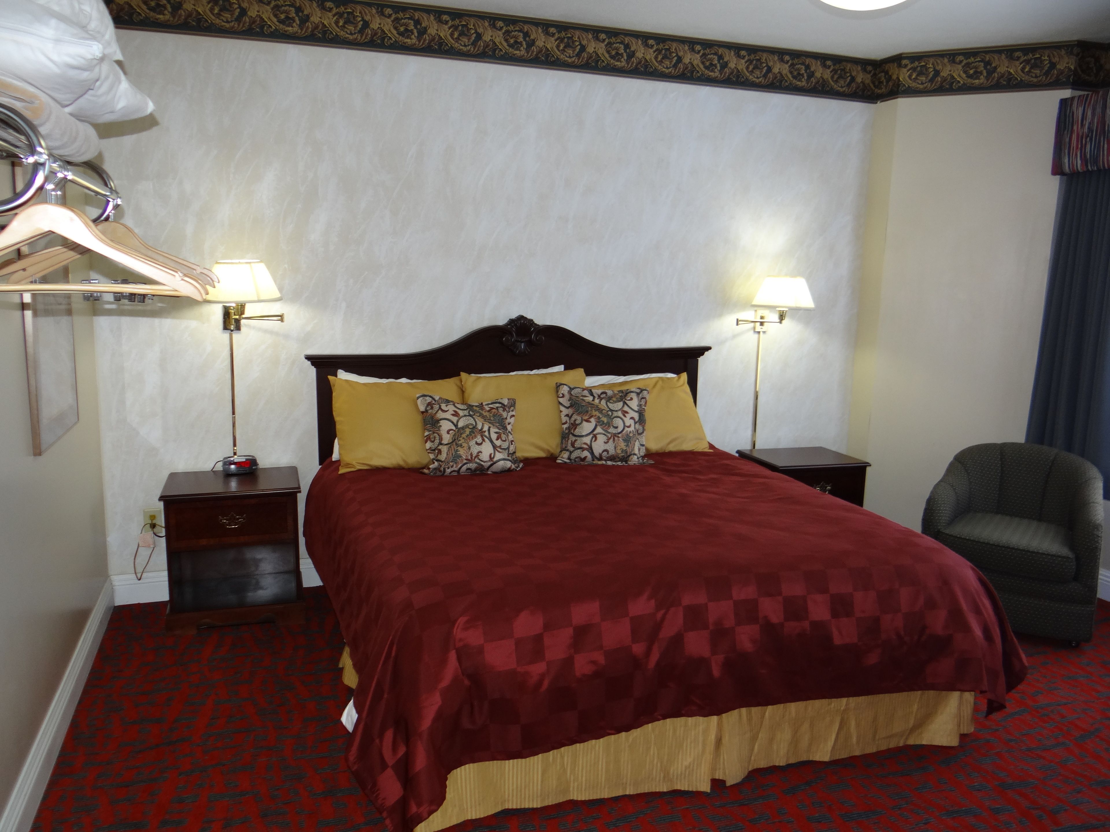 Ein Hotelzimmer mit einem großen Bett, zwei Nachttischlampen, einem Sessel und einem Kleiderschrank.