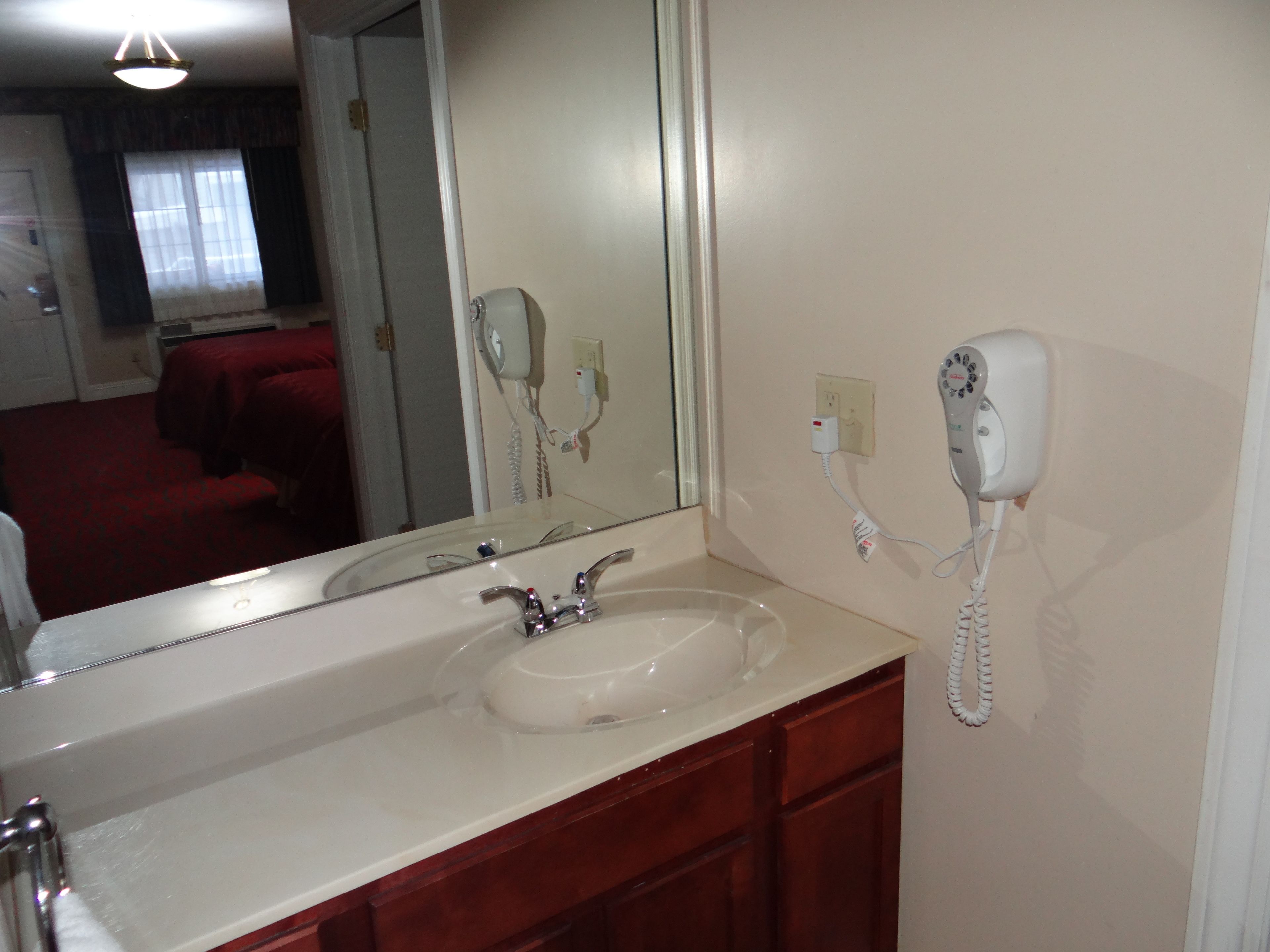 A bathroom with a sink, mirror, and hairdryer.