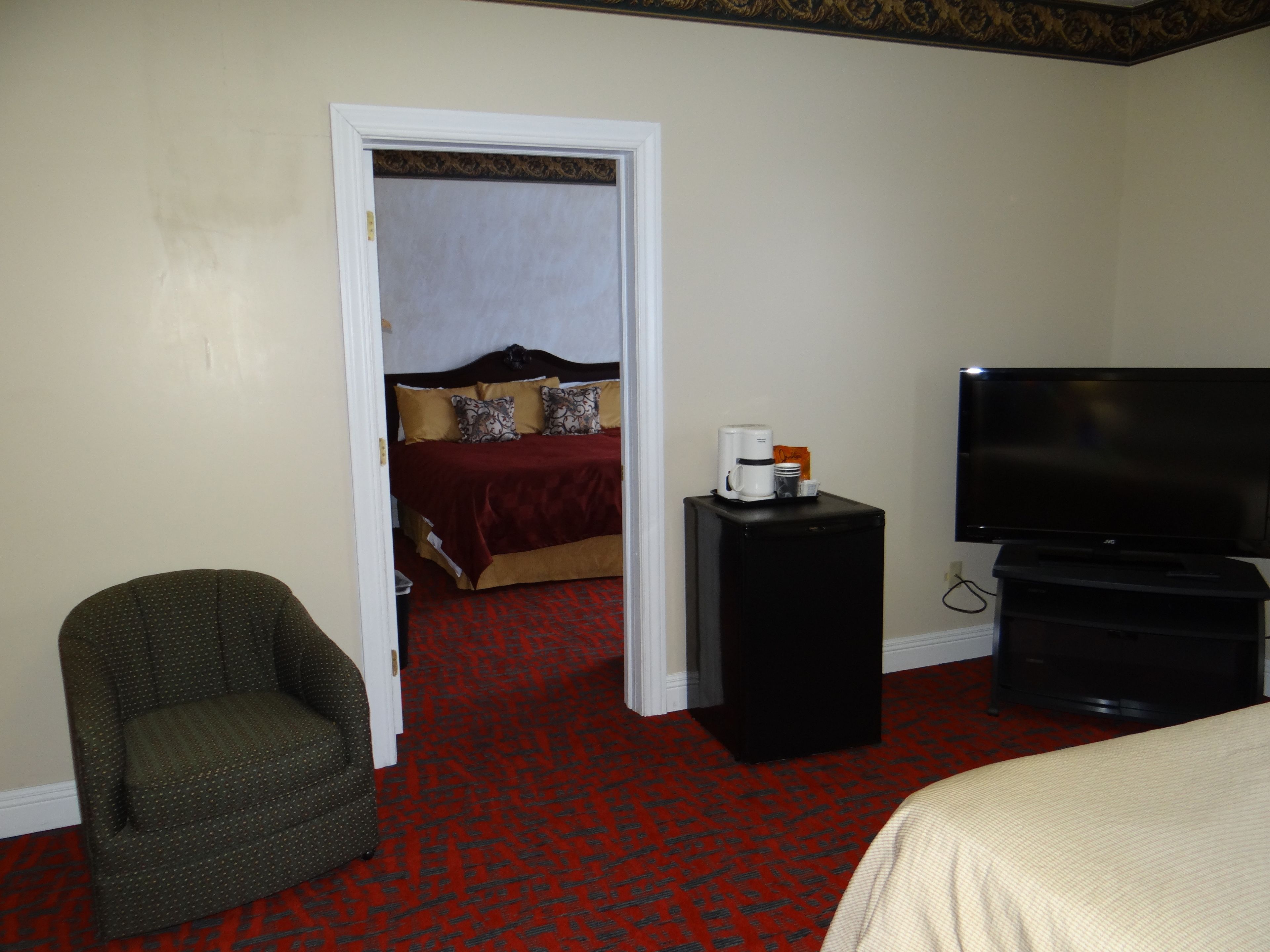 Une chambre d’hôtel équipée d’un lit, d’une télévision, d’une machine à café et d’une chaise.