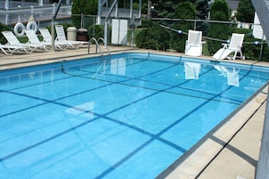 Una piscina al aire libre de temporada, sillones reclinables de piscina