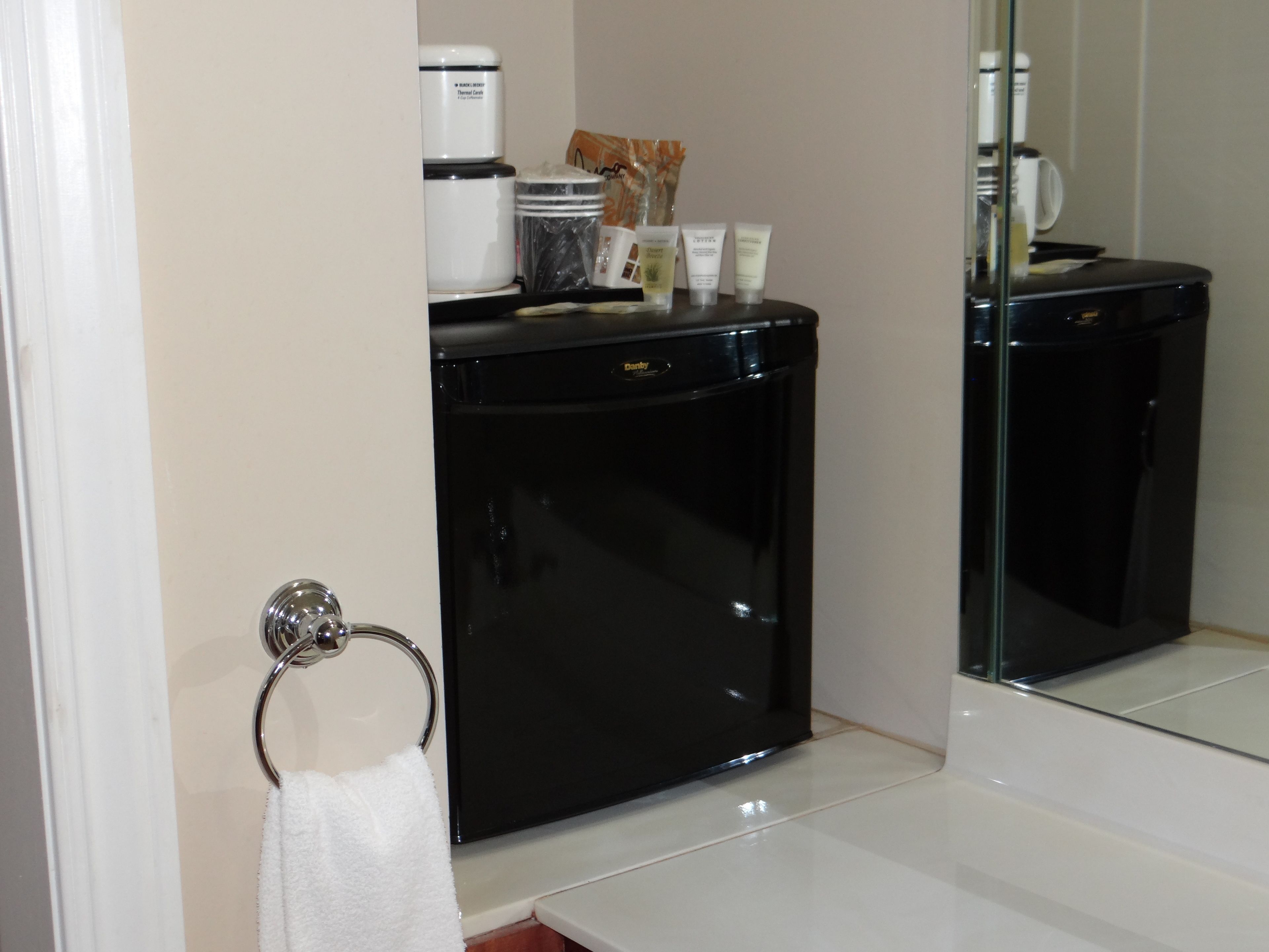 A compact bathroom with a black vanity, a towel ring, and toiletries on the counter.