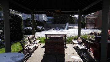 A covered outdoor seating area with benches and a brick table, leading to a building labeled "OFFICE".