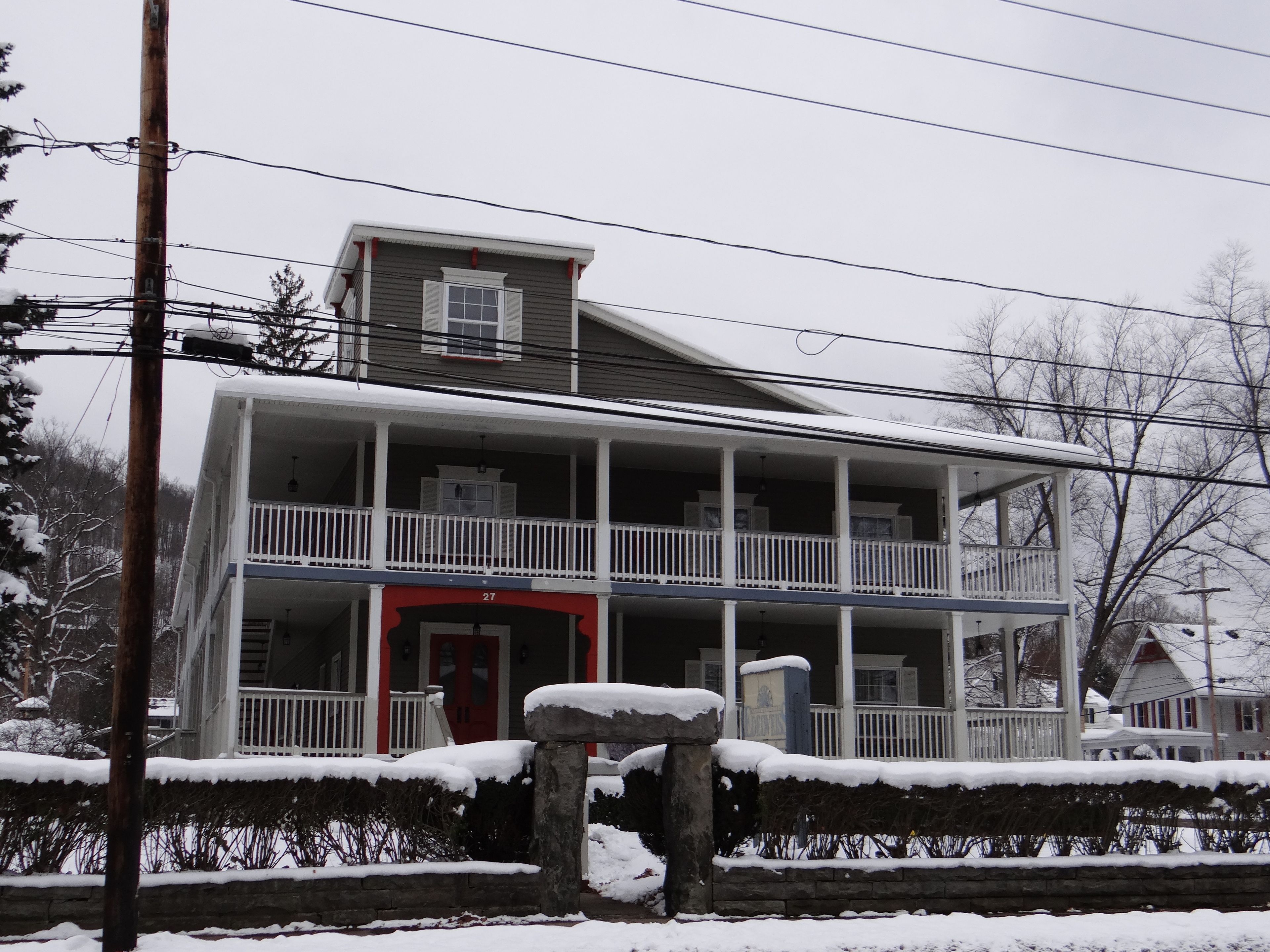 A two-story house with a porch and a red door.