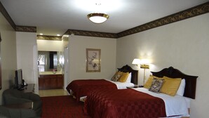 Habitación de hotel con dos camas, televisión, escritorio y suelo cubierto de moqueta roja.