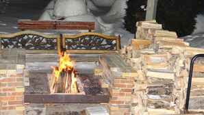 Una chimenea con rejilla metálica, rodeada de leña apilada.