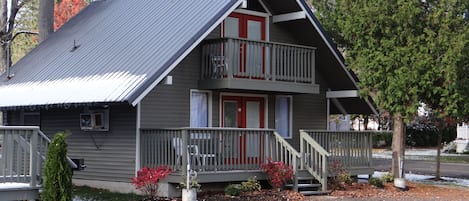 A two-story cabin with a balcony, a front porch, and a small front yard.