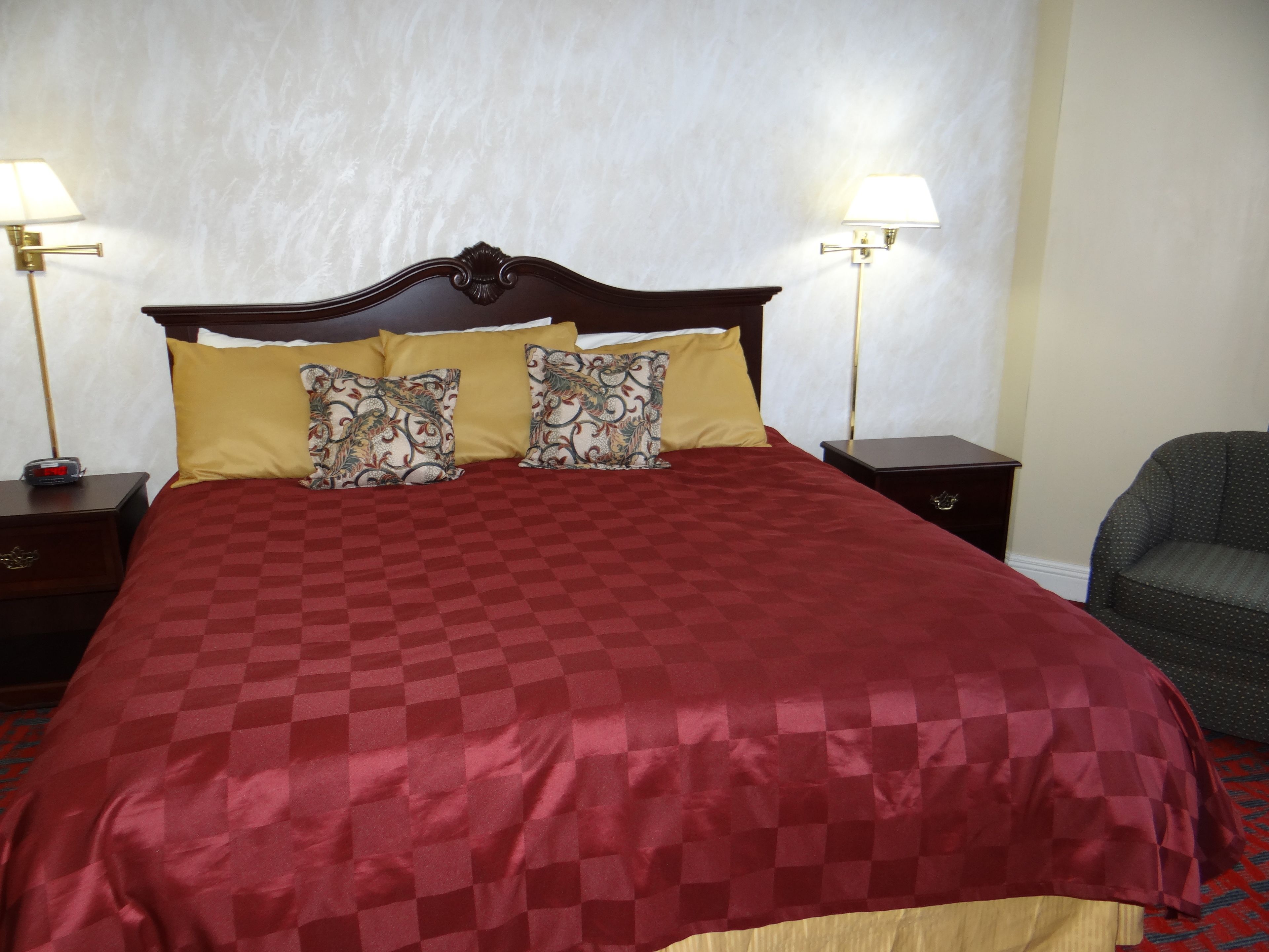 Una habitación de hotel con una cama grande, dos lámparas de noche, una mesita de noche y una silla.