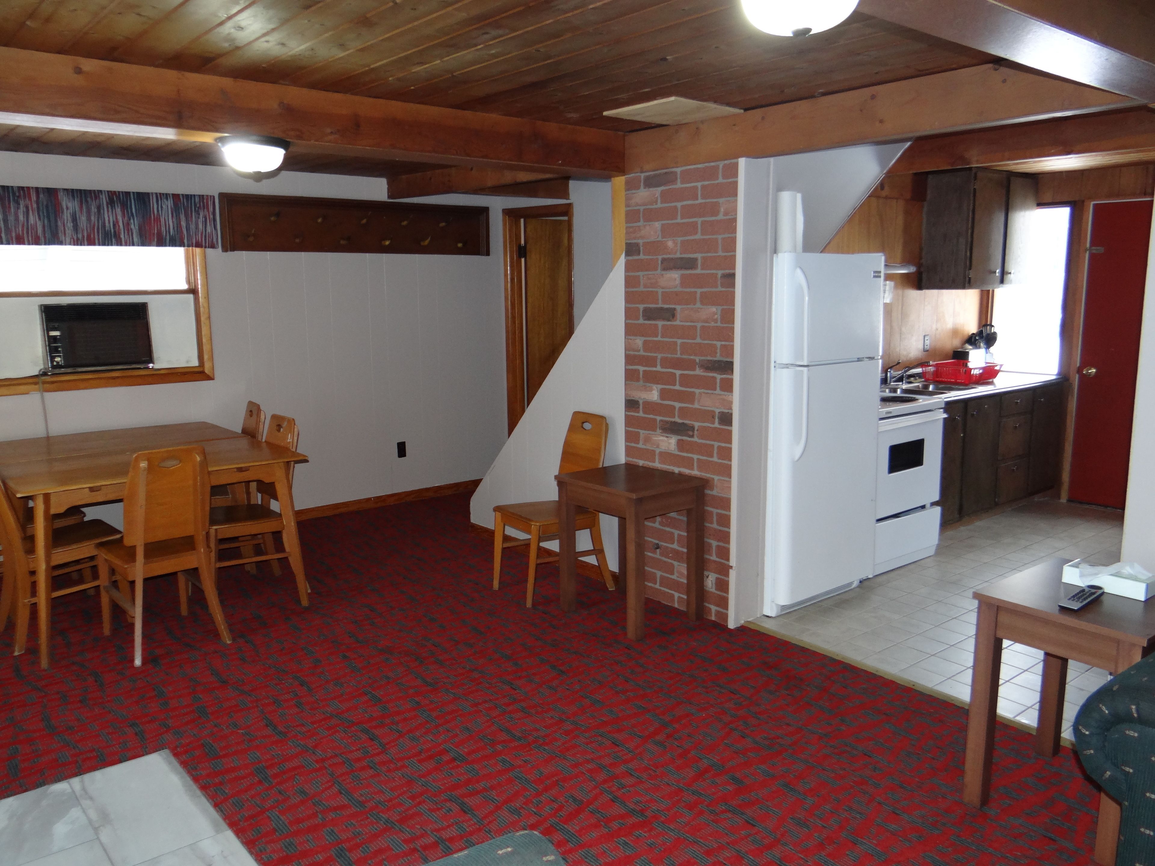 A compact living space with a dining area, a kitchen, and a staircase.