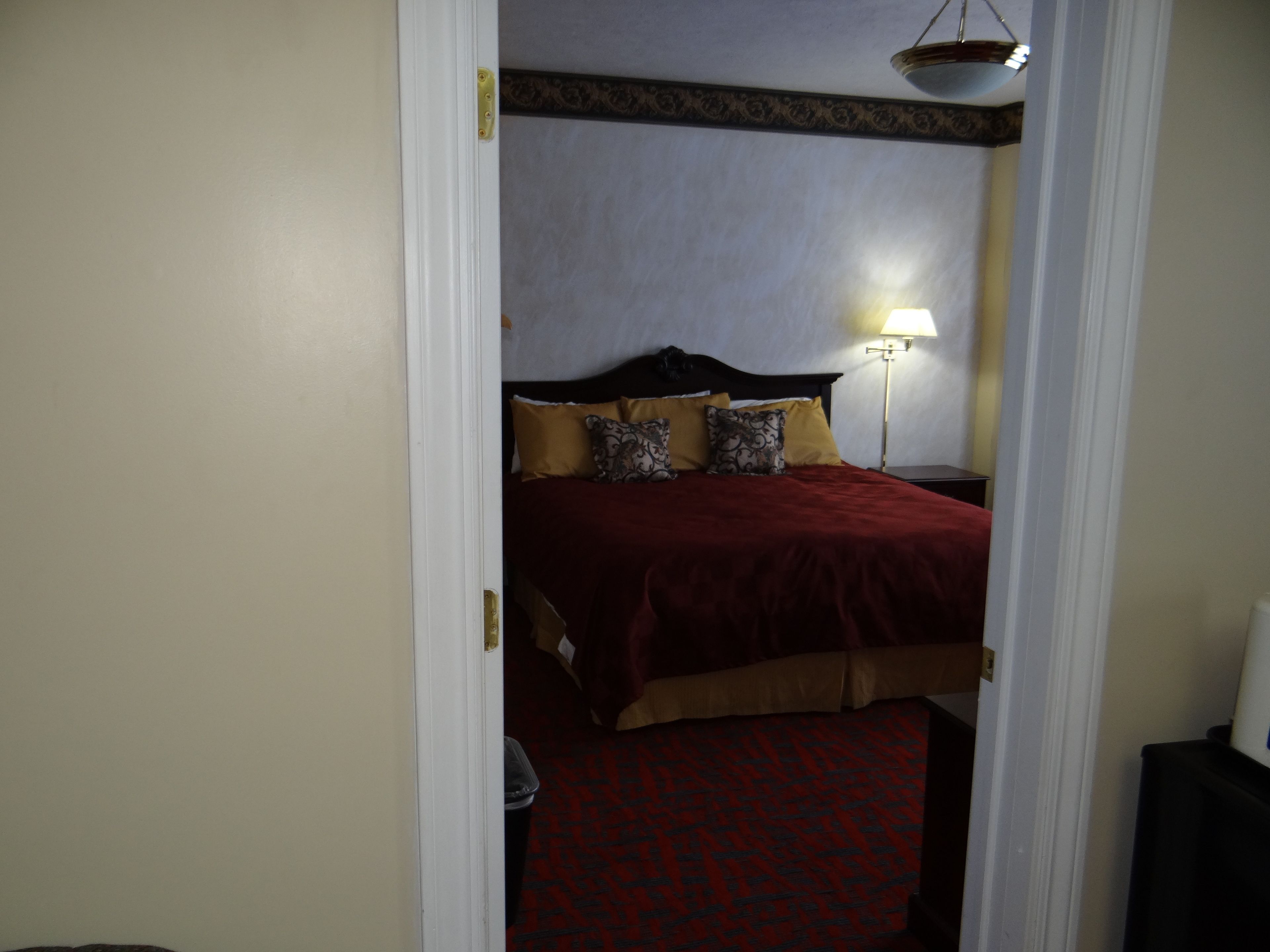 A hotel room with a bed, a nightstand, and a lamp.