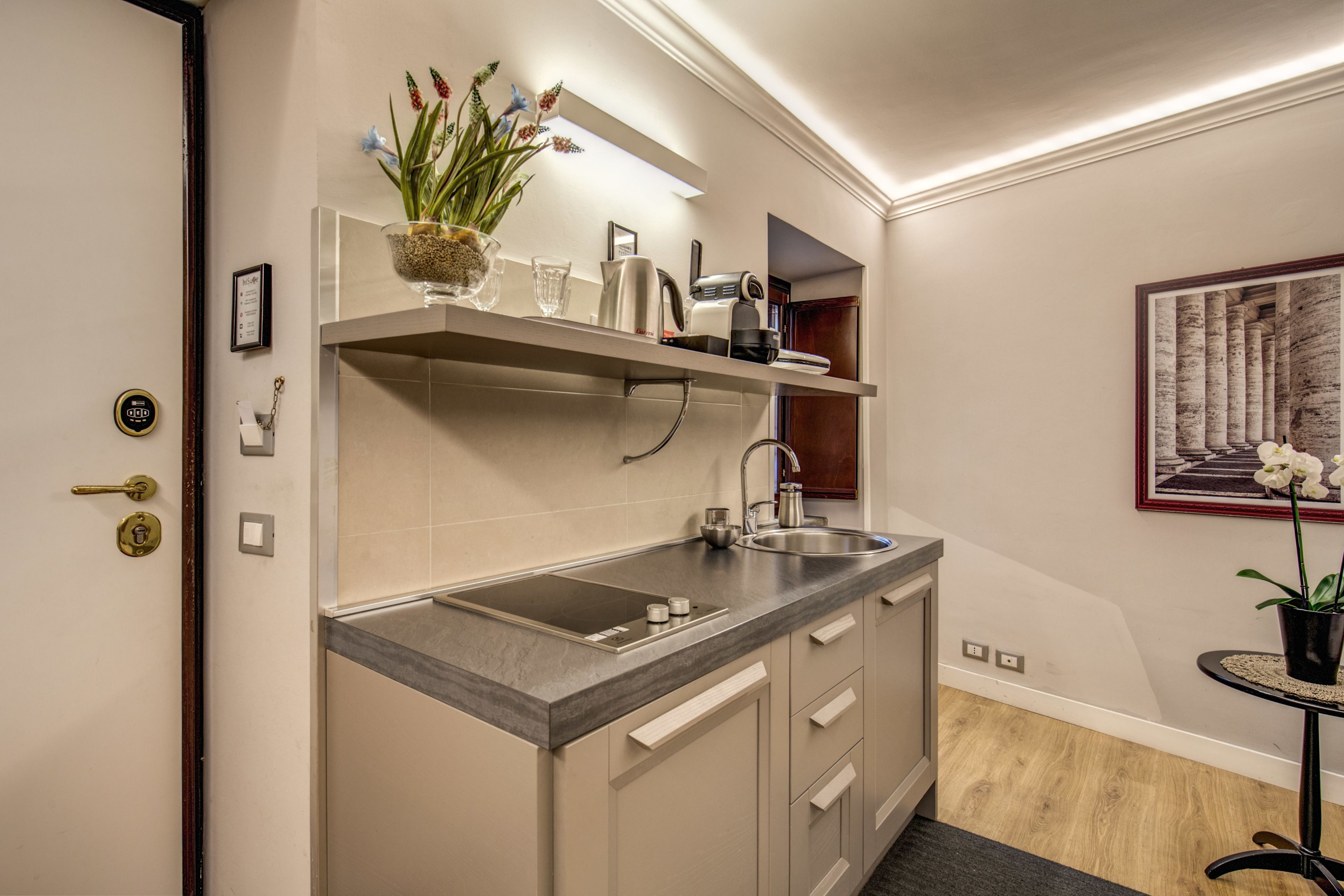 A compact kitchen with a built-in sink, a countertop, and a small table with a potted plant.
