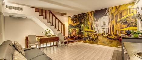 A modern living room with a staircase, a dining area, and a kitchen.