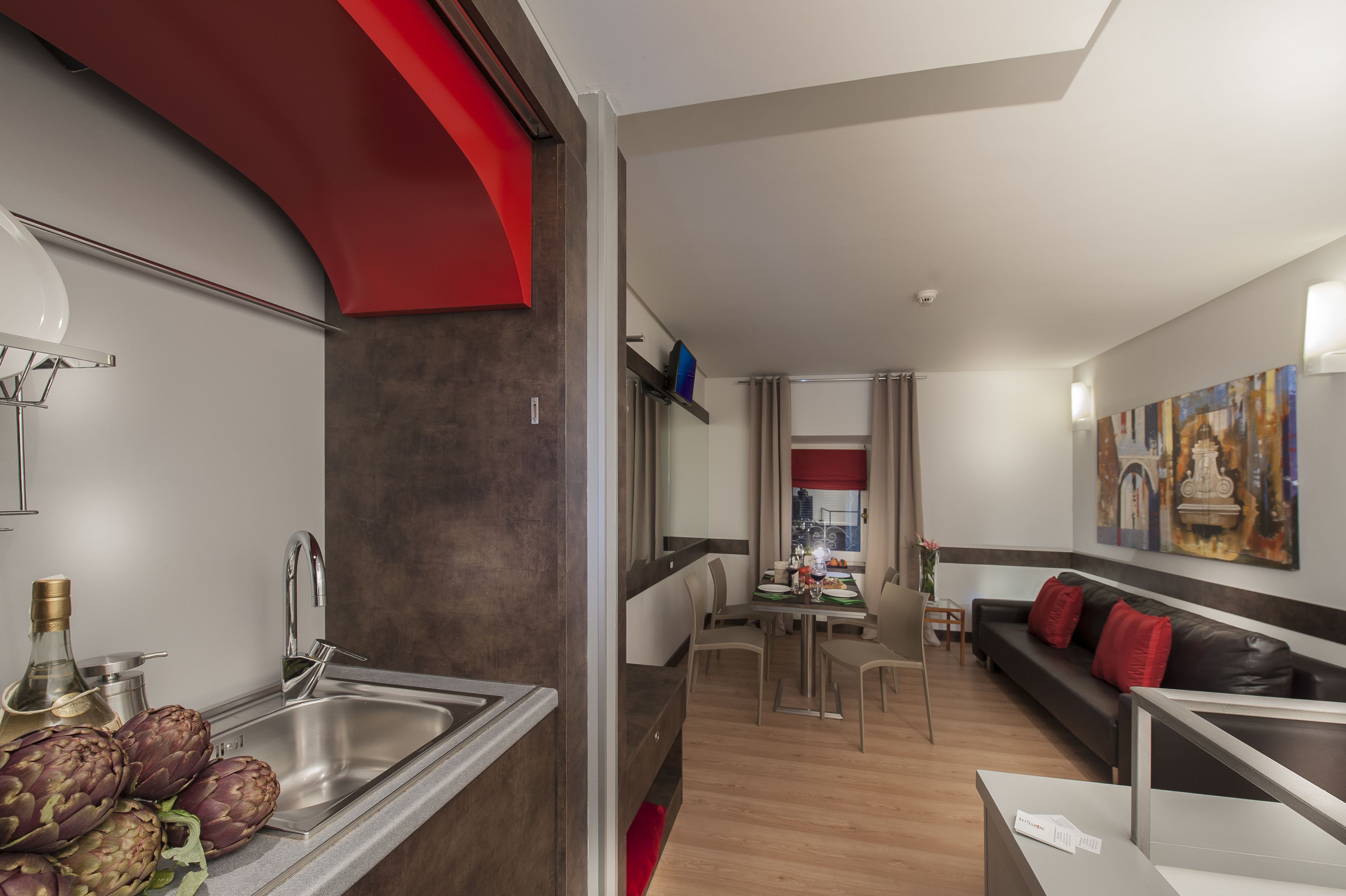 A modern kitchen with a stainless steel sink and a dining area with a table and chairs.