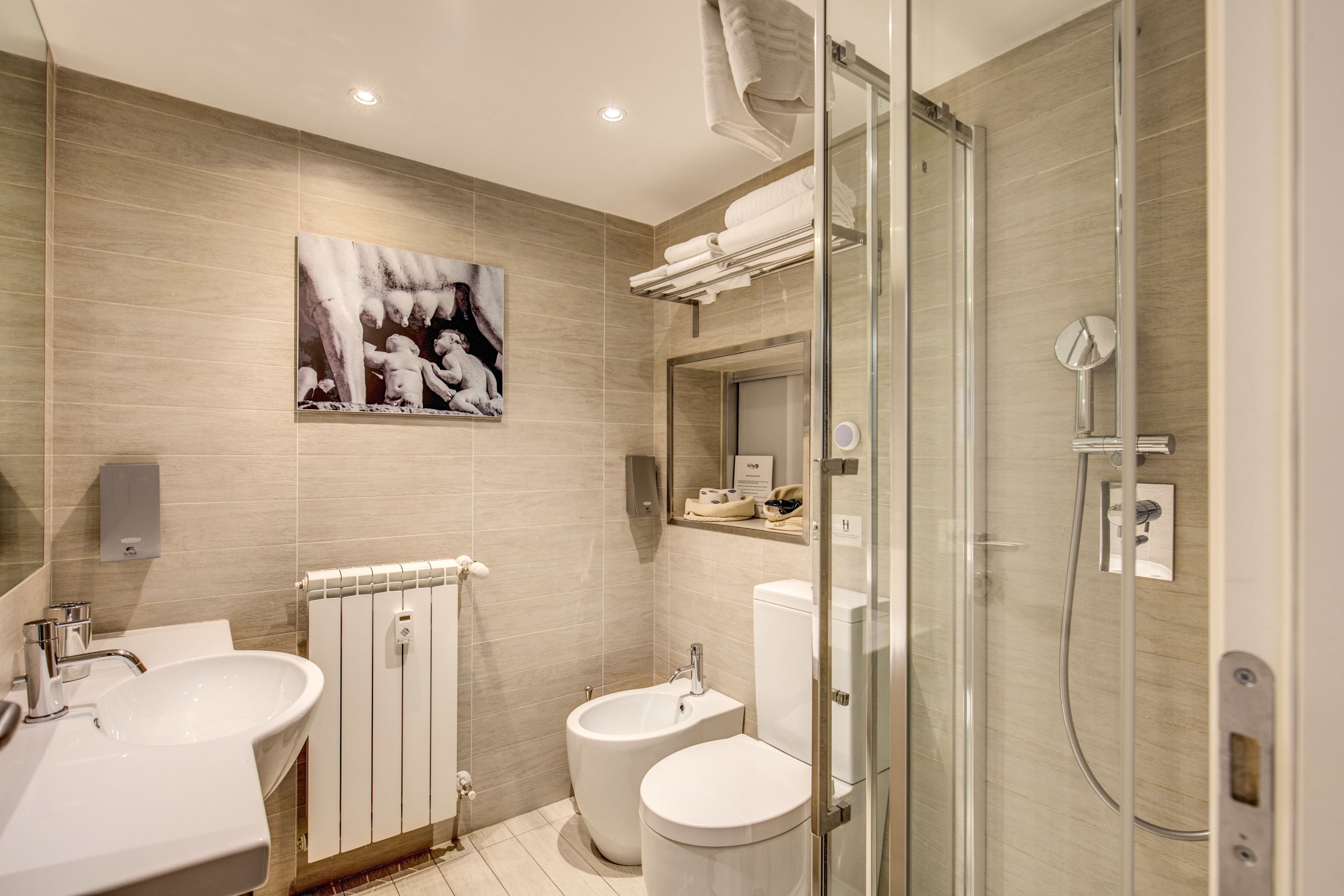A modern bathroom with two sinks, a bidet, a toilet, a glass shower enclosure, and a towel rack.