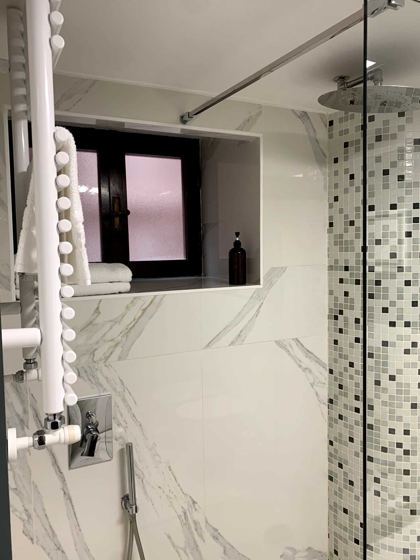 A modern bathroom with a shower, a vanity with a mirror, and a window above the sink.