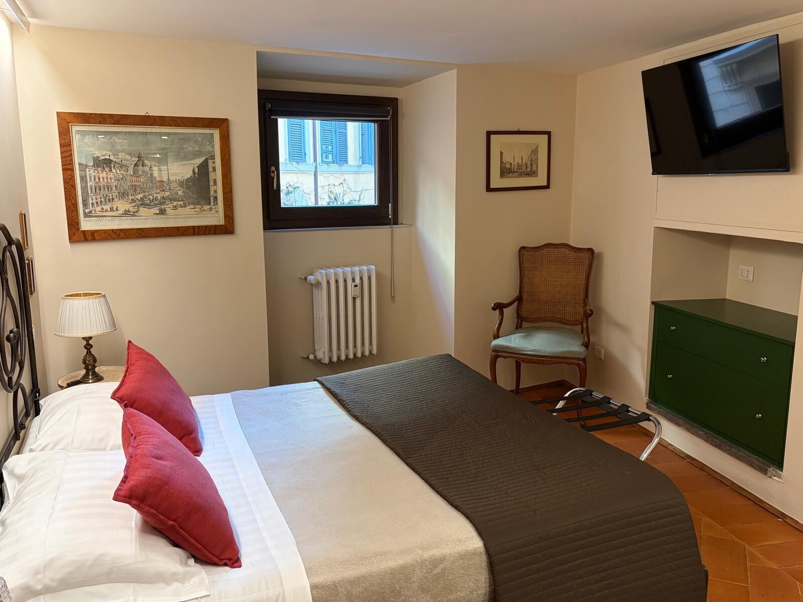 Une chambre à coucher avec un lit, une chaise, un radiateur, un téléviseur et une armoire verte.