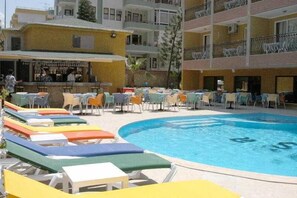 Una piscina al aire libre, sombrillas, tumbonas