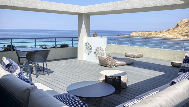 A covered outdoor seating area with a view of the sea, featuring a sofa, chairs, and a small table. - Best Western Premier Santa Maria (L'Île-Rousse)