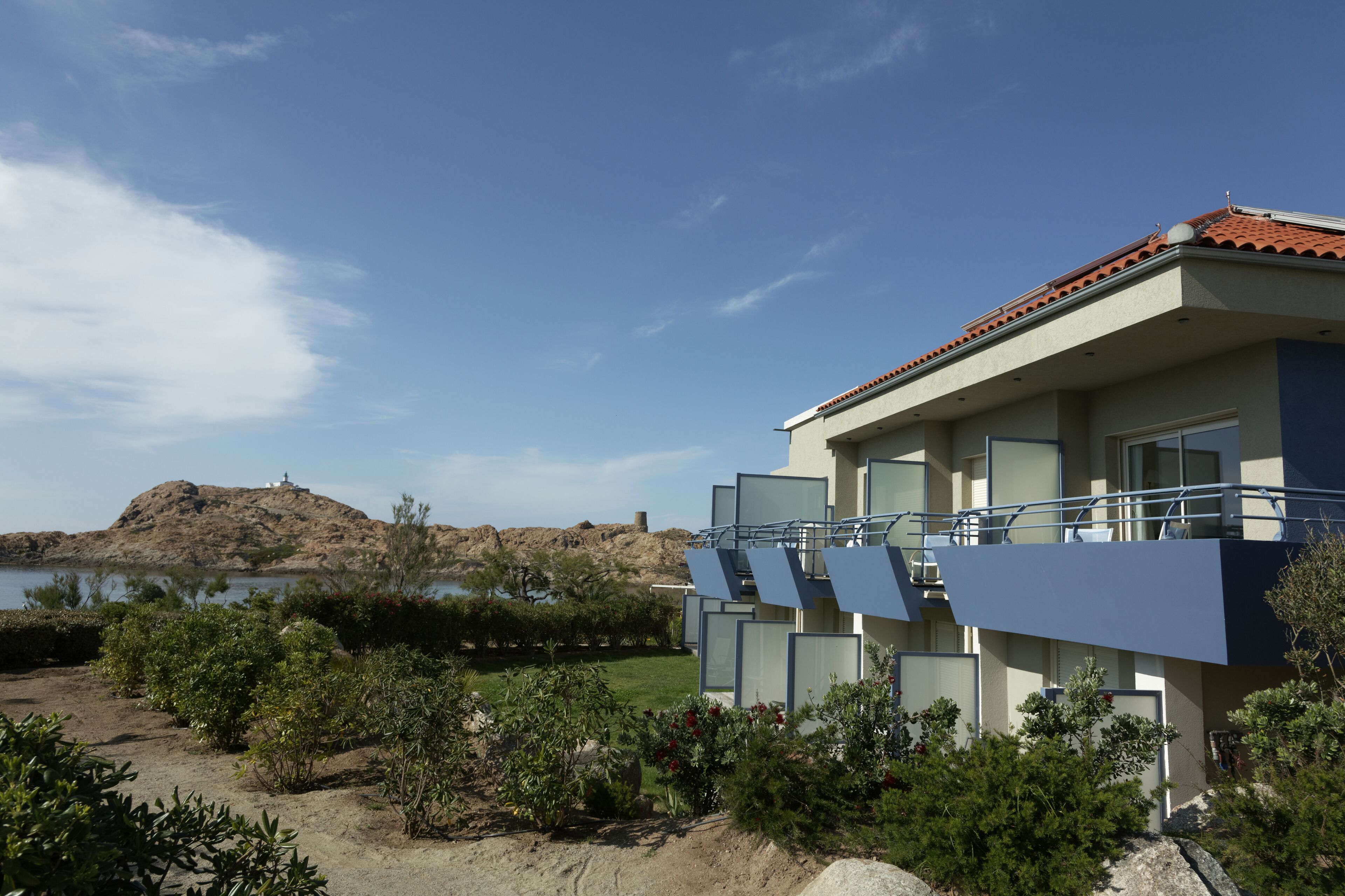 Un hotel moderno con techo plano, amplias ventanas y vistas a un lago y colinas.