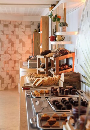 A buffet with various breads, pastries, and desserts.