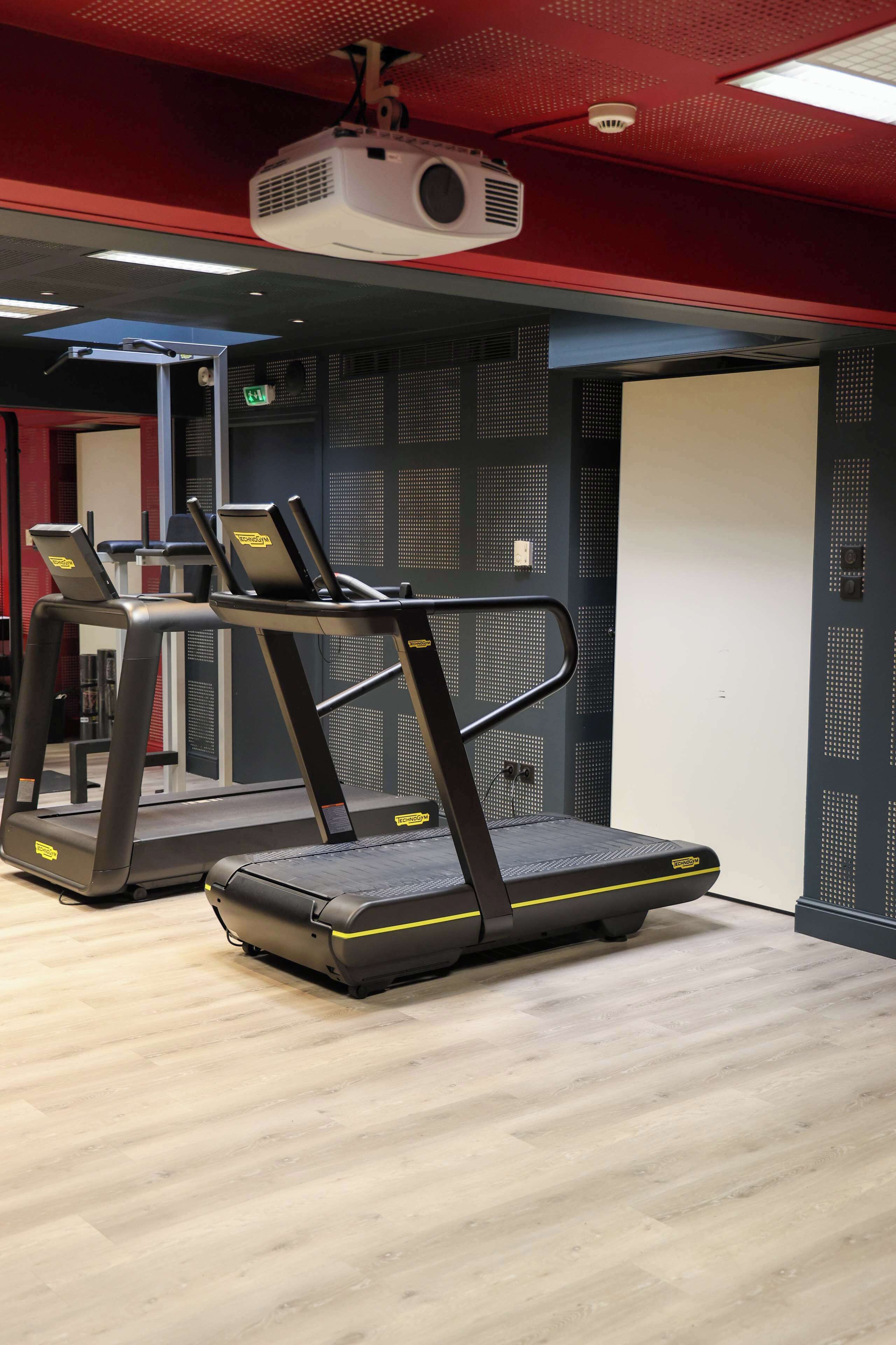 A gym with treadmills and a projector on the ceiling.
