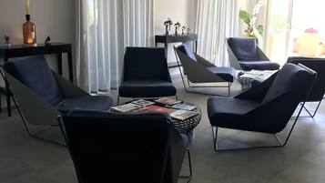 A modern living room with black leather chairs, a small table with magazines, and a decorative bottle.