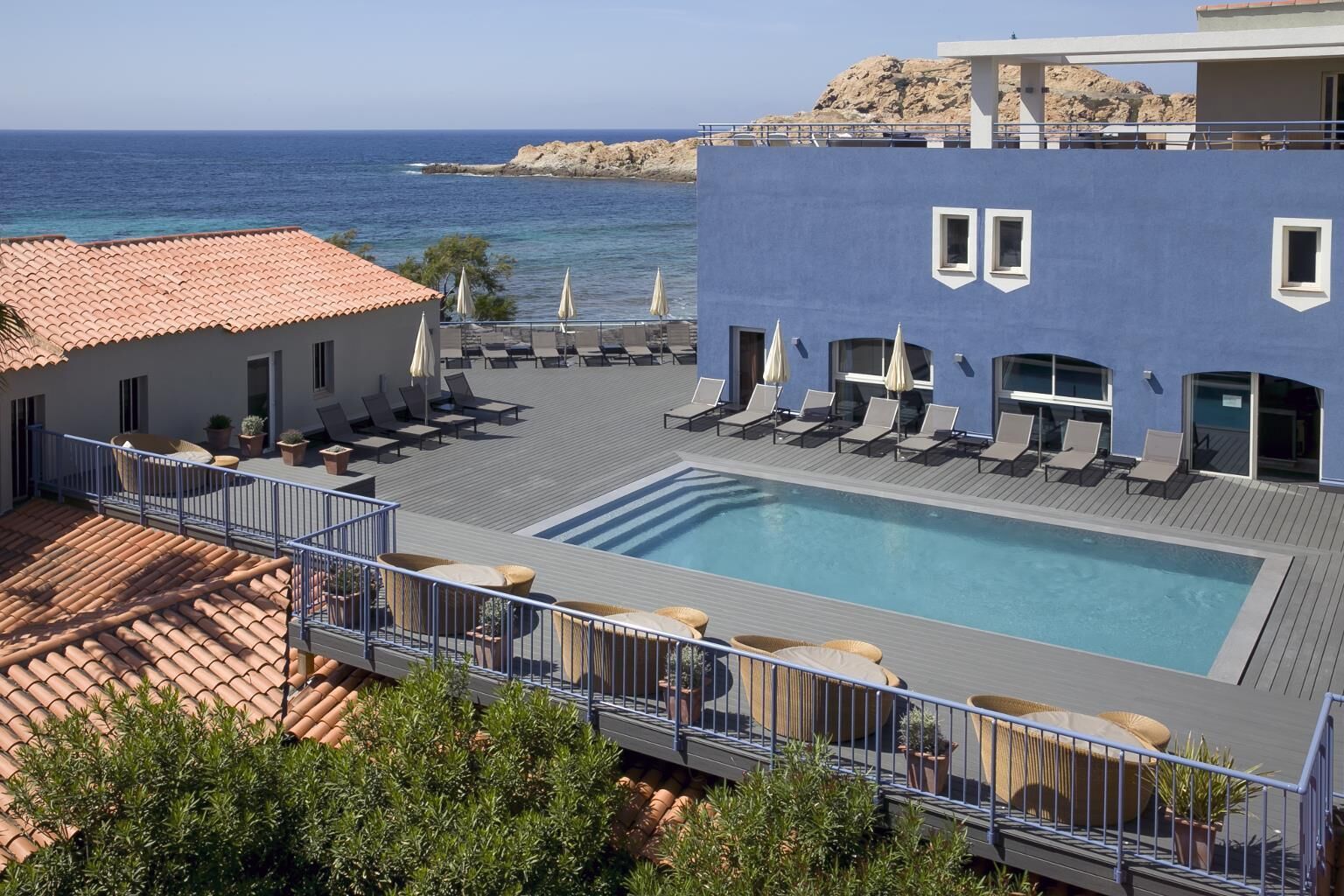 Ein Pool auf dem Dach mit Liegestühlen und Sonnenschirmen mit Blick aufs Meer.