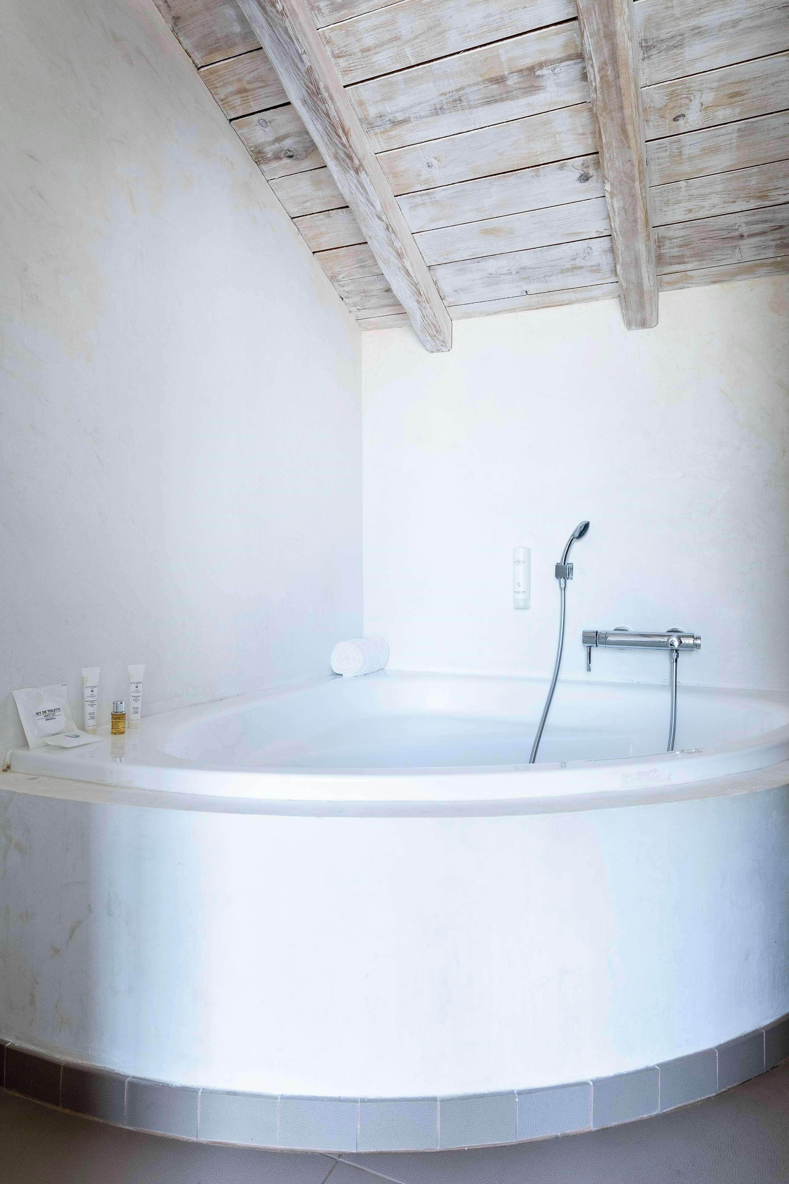 Un baño con una bañera grande, ducha y techo de madera.