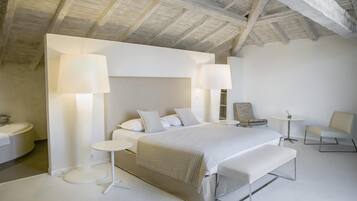 Une chambre moderne avec un grand lit, deux lampes de chevet, un banc, une chaise et une petite table.