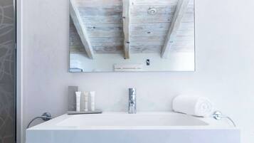 Ein Badezimmer mit einem weißen Waschbecken, einem Spiegel und Holzbalken an der Decke.