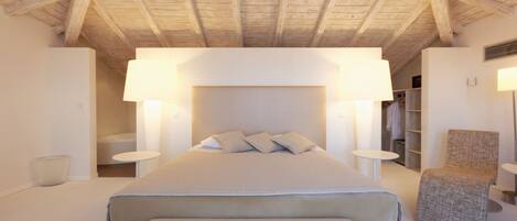 A bedroom with a large bed, bedside tables, a chair, and a wardrobe.
