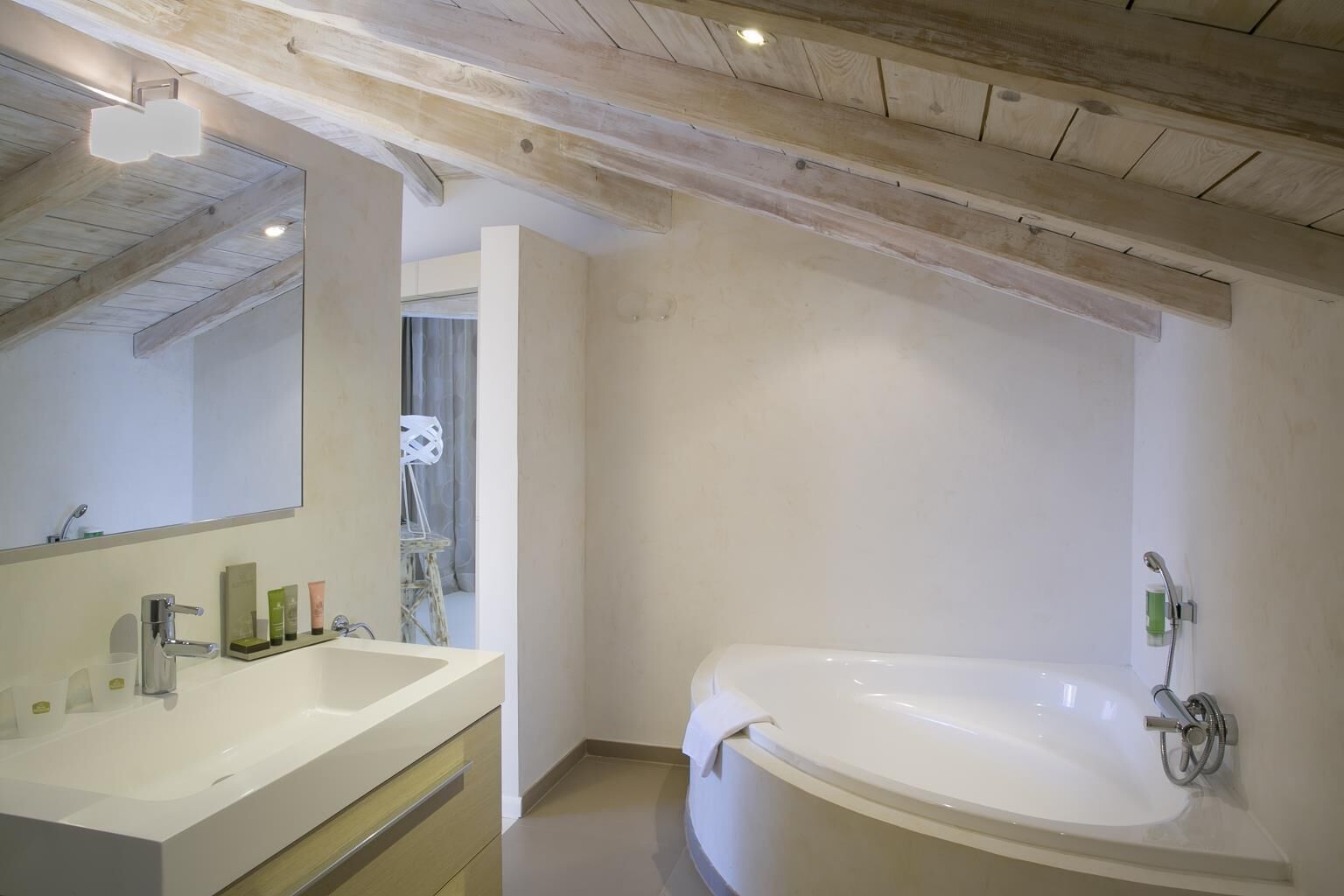 Un baño moderno con una bañera grande, un tocador con espejo y una zona de ducha.
