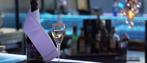 A bottle of Casanova wine, a glass of white wine, and a small plate of nuts on a bar counter.