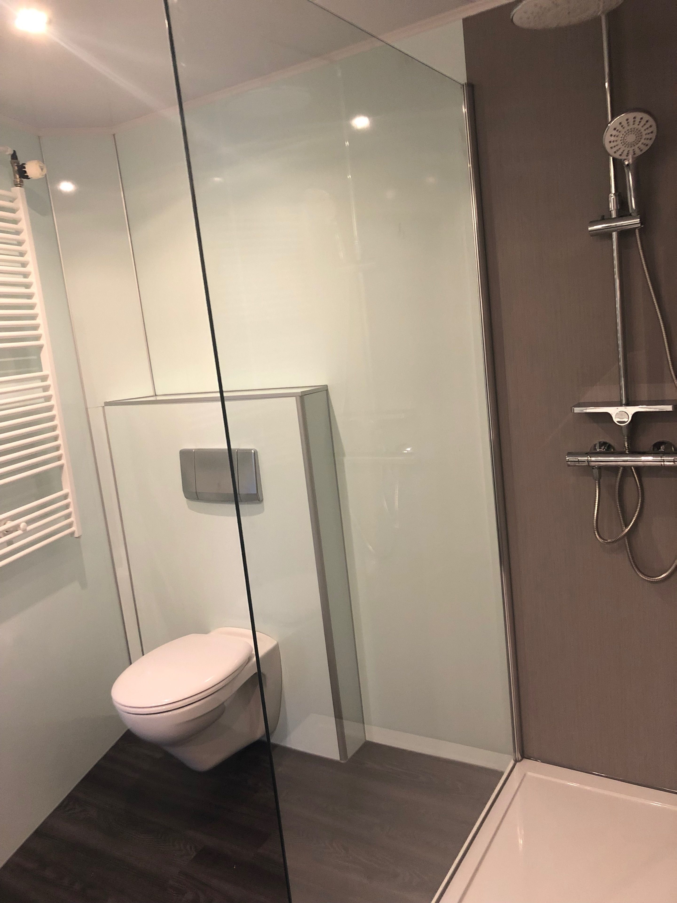 A modern bathroom with a glass-enclosed shower, a toilet, and a bathtub.
