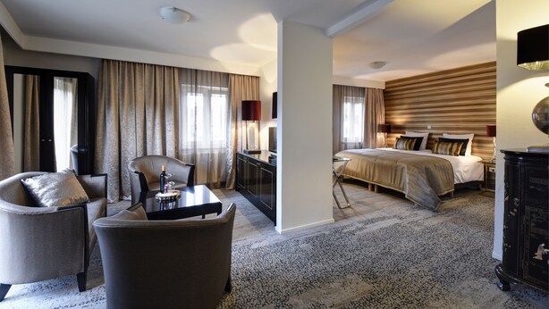 Une chambre d’hôtel comprenant un lit, un bureau avec une chaise, un canapé et un grand miroir.