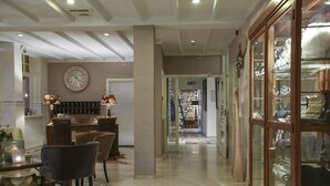 Un hall d’hôtel comprenant un espace repas, une grande horloge et une vitrine exposant divers objets.