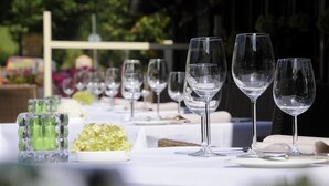 Une table dressée pour un repas, avec de la vaisselle transparente et un petit bol contenant une garniture verte.
