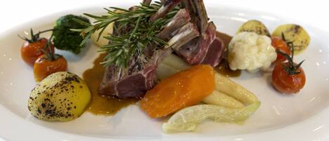 A plate of food with lamb chops, potatoes, carrots, and cherry tomatoes.