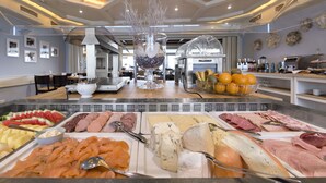 Un buffet proposant une variété de plats, notamment des viandes, des fromages et des fruits.
