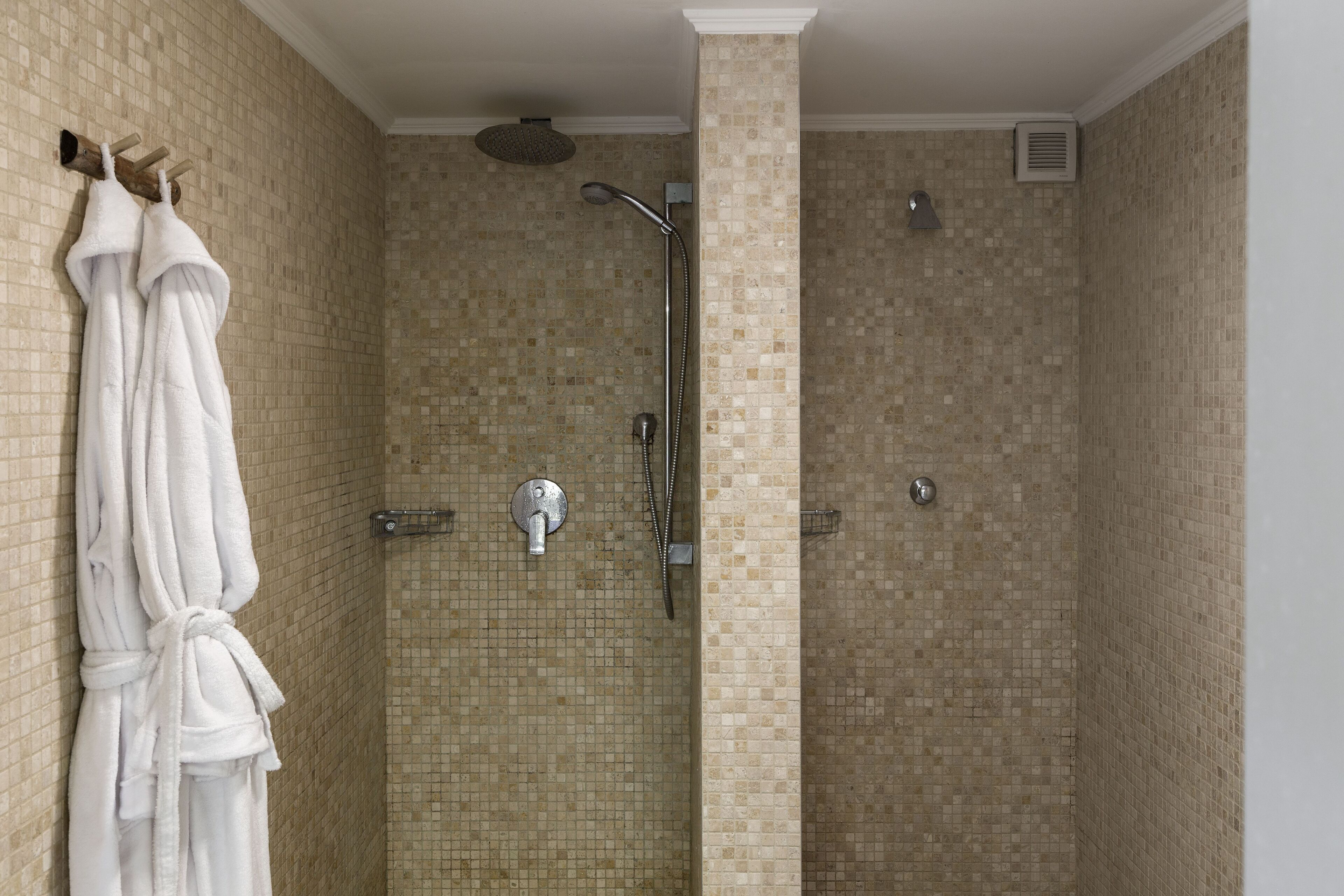 Une douche équipée d’un pommeau de douche à effet pluie, d’un pommeau de douche à main et d’un porte-serviettes avec des serviettes.