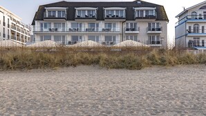 Un immeuble à plusieurs étages doté de balcons, situé juste à côté d’une plage de sable.