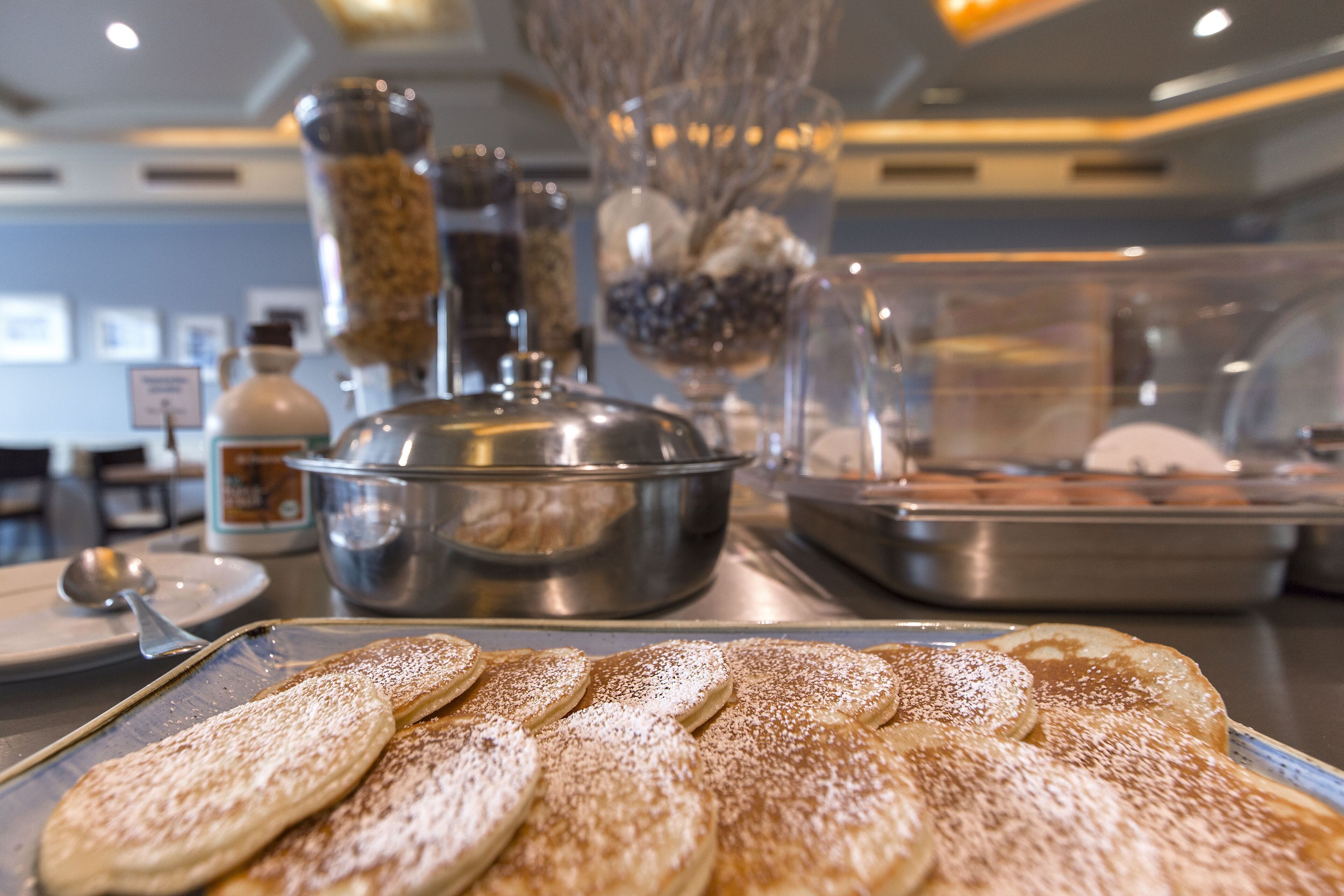Buffet com variedade de alimentos, incluindo uma bandeja de doces polvilhada com açúcar de confeiteiro.