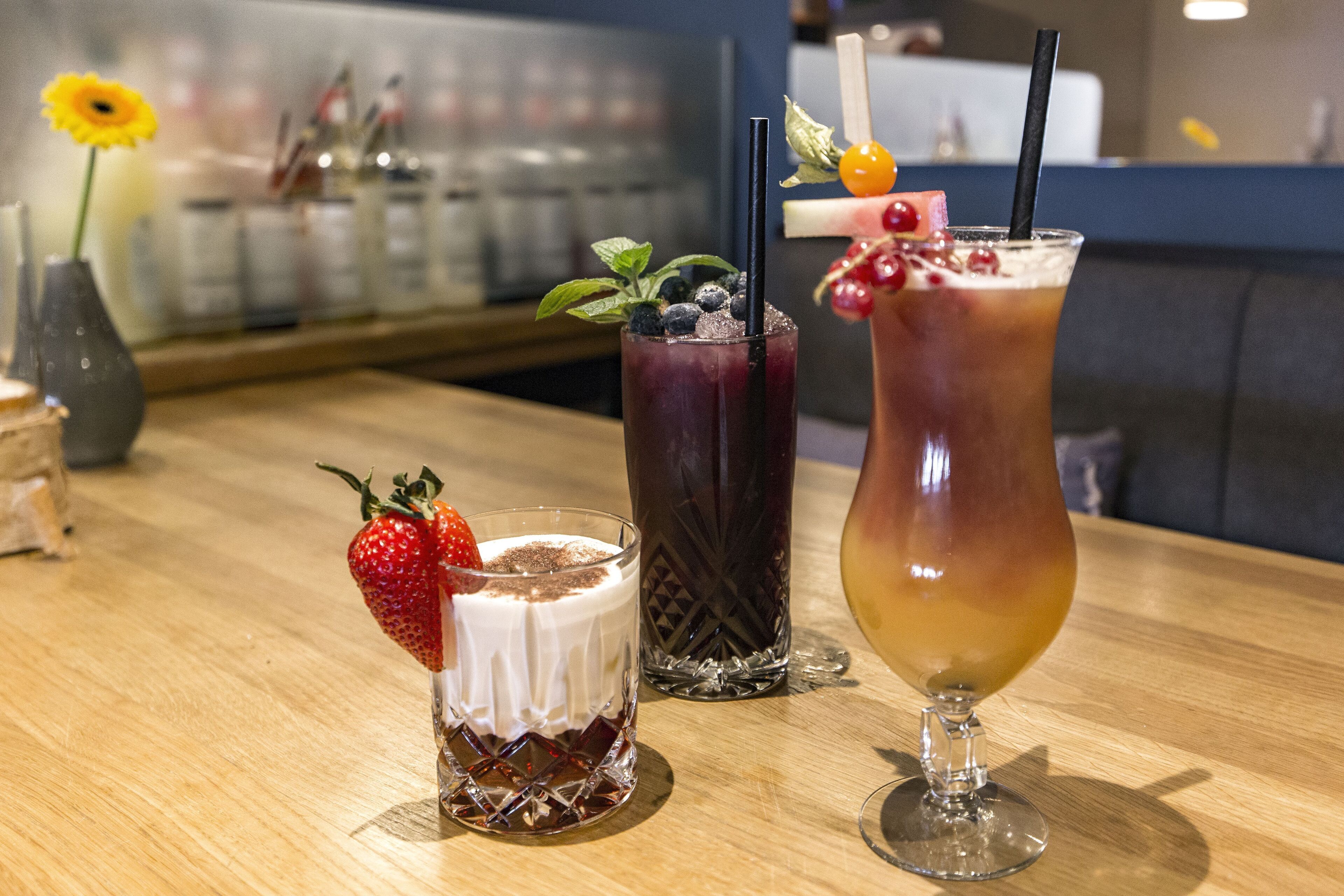 Three drinks on a wooden table with a blurred background.