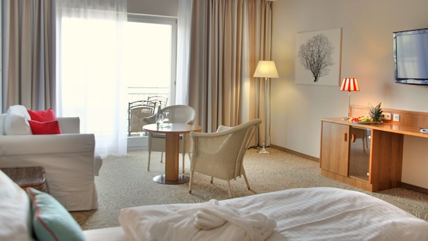 Une chambre d’hôtel comprenant un lit, un bureau, une chaise, un canapé, une table à manger et un téléviseur.