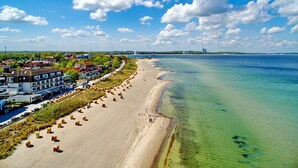 Un hôtel situé sur la côte, avec vue sur la plage, de nombreuses chambres et un ciel dégagé.