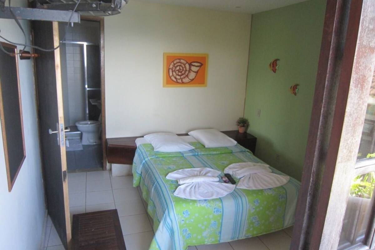 A bedroom with a bed, a painting, and a bathroom.
