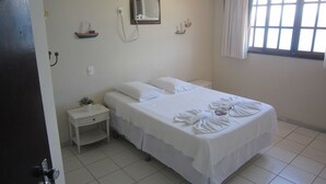A bedroom with a bed, bedside tables, a wall-mounted air conditioner, and a window with curtains. - Pousada Pier 7400 (Angra dos Reis)