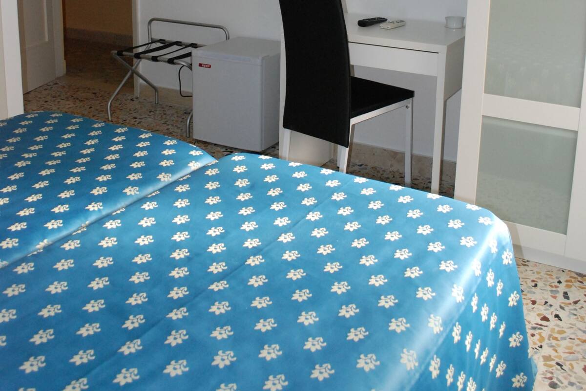 Una habitación con una cama, un escritorio, una silla, un televisor y un extintor.