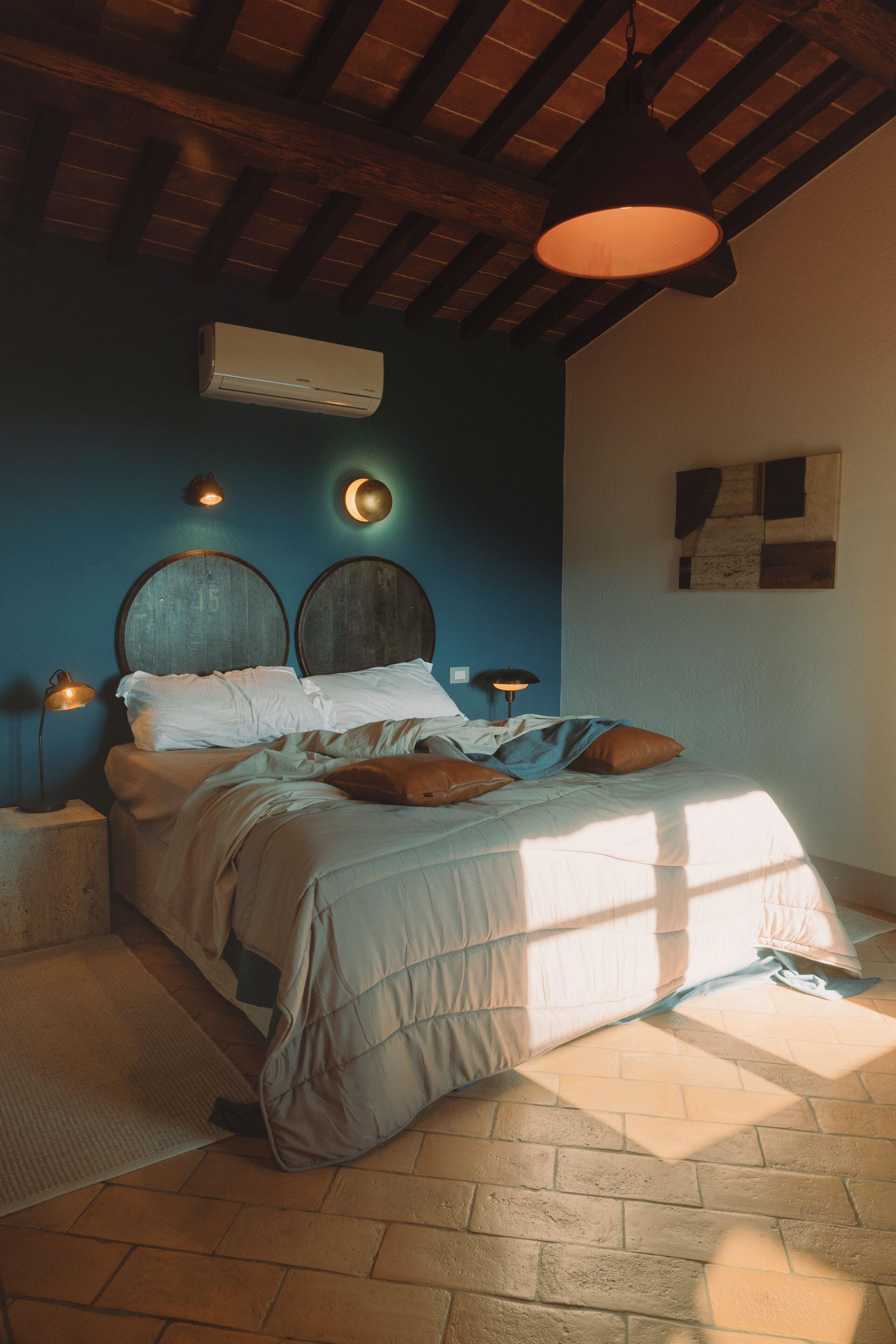 A bedroom with a bed, bedside lamps, an air conditioner, and a wall clock.