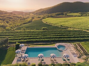 A pool area with lounge chairs and umbrellas, surrounded by vineyard rows and hills. - Tuscan Relais Il Serraglio (Montepulciano)
