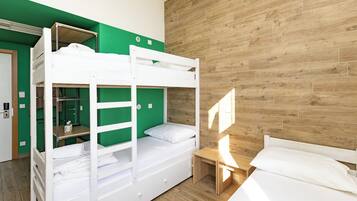 A bunk bed room with a wooden floor, green walls, and a wooden headboard.